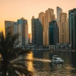 View of Dubai Marina skyscrapers with a boat on the water during a beautiful sunset.